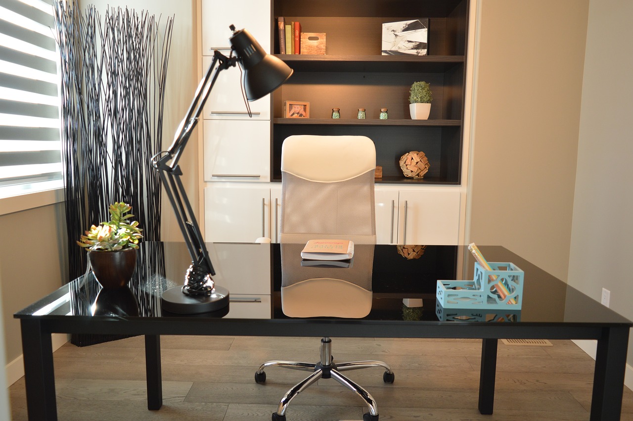 Shot of a modern home office with a black desk and white roller chair. 